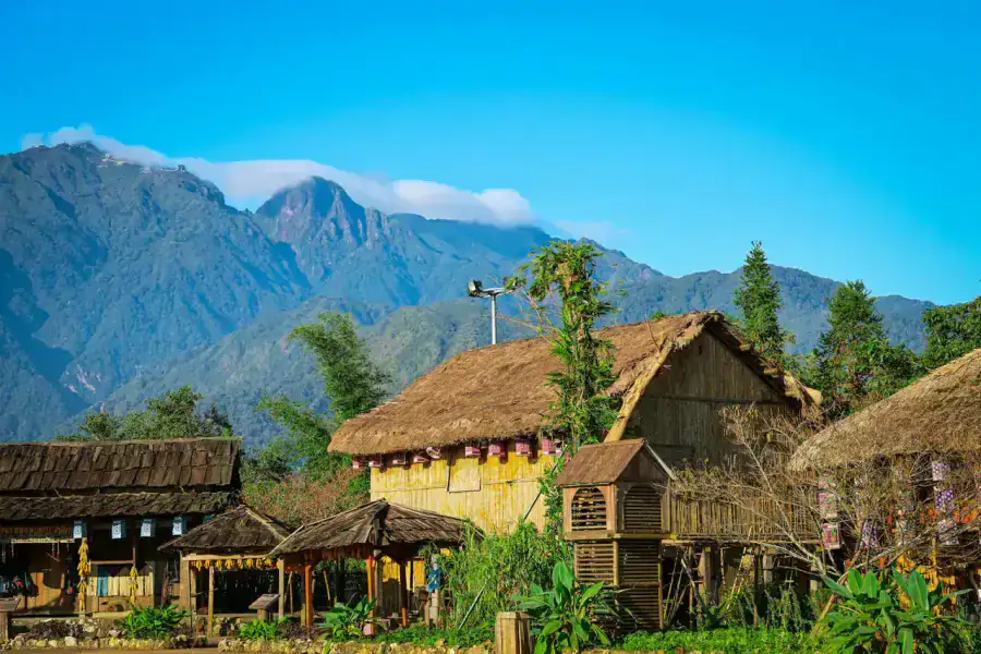 Traditional thatched stilt houses in Sapa village with Hoang Lien Son mountains